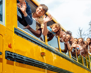 scuolabus con bambini che salutano dai finestrini