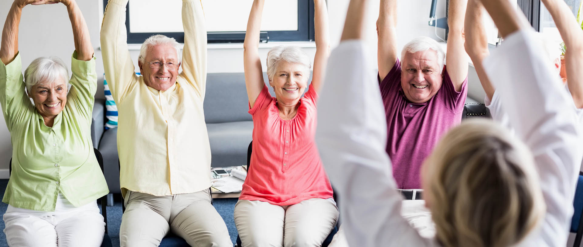 gruppo di anziani e operatrice in casa di riposo che fanno ginnastica